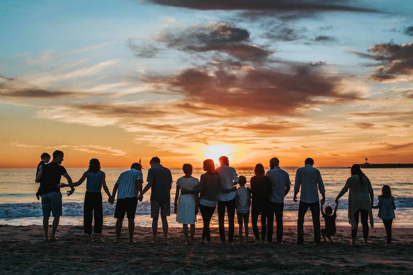 A large family holding hands on a beach at sunset